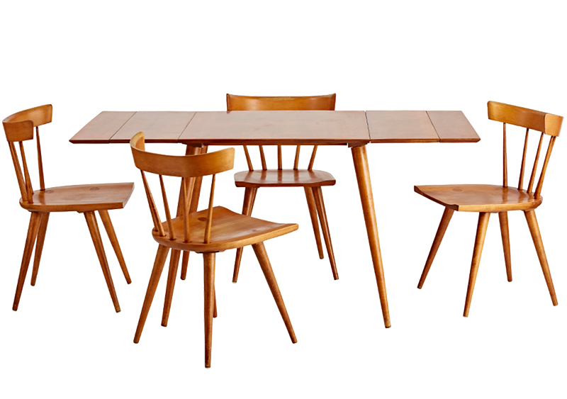 A dining table set by Paul McCobb. The natural wood shines through on this set that has tapered table and chair legs and a minimalistic style.