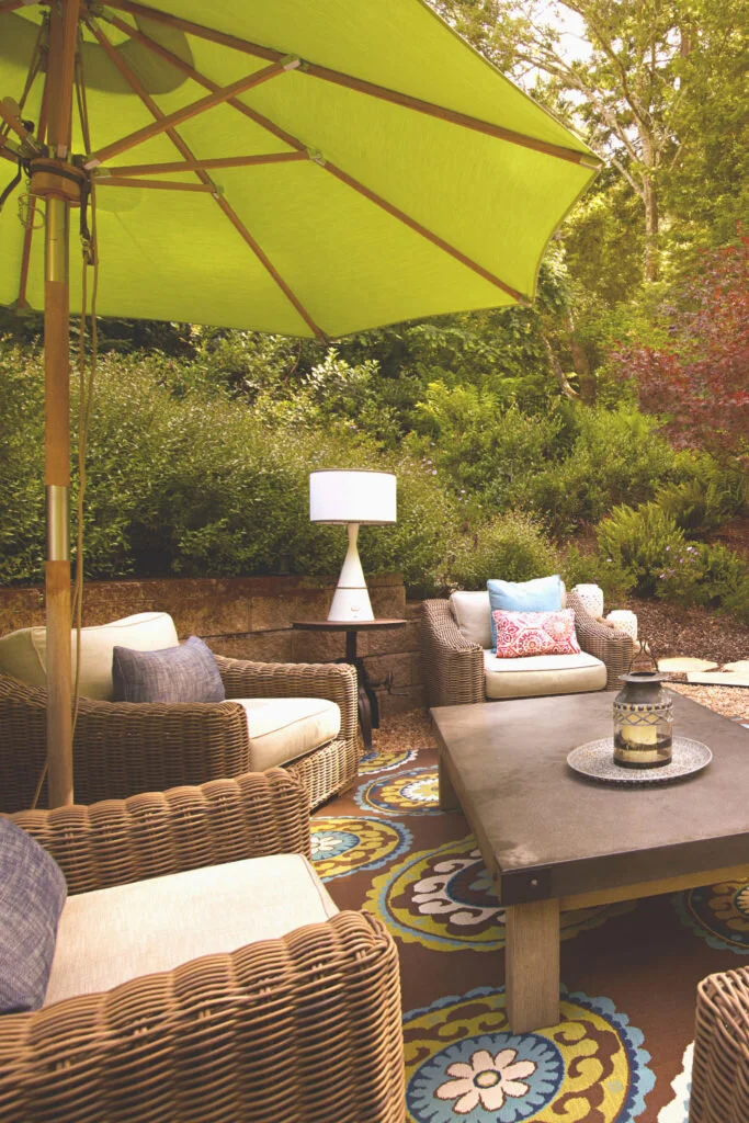 An outdoor space with comfortable wicker chairs, a low coffee table and a green umbrella. Work from home outside and inject some fresh air into what you do.