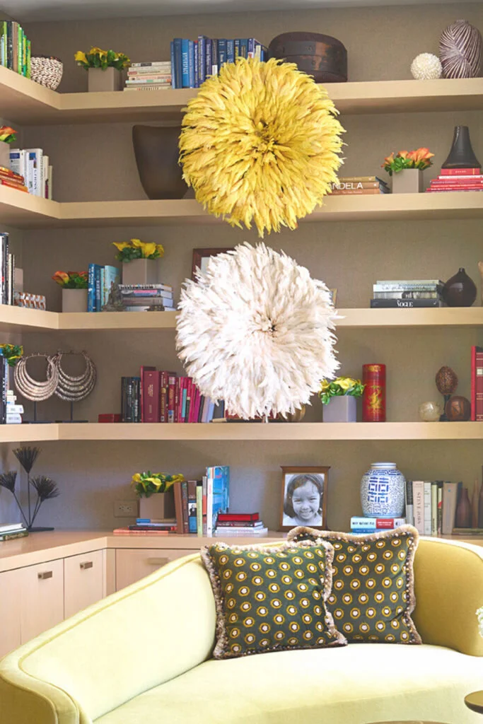 A built in bookcase stores objects and books behind a lime green couch.