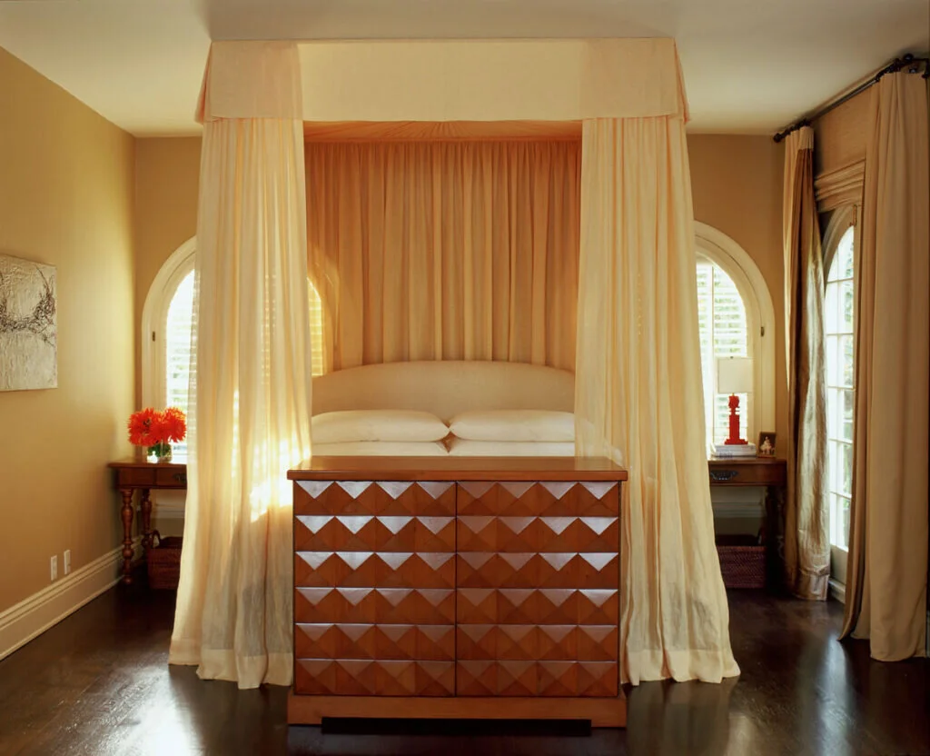 A luxurious bed with canopy curtain, natural lighting, and side tables.
